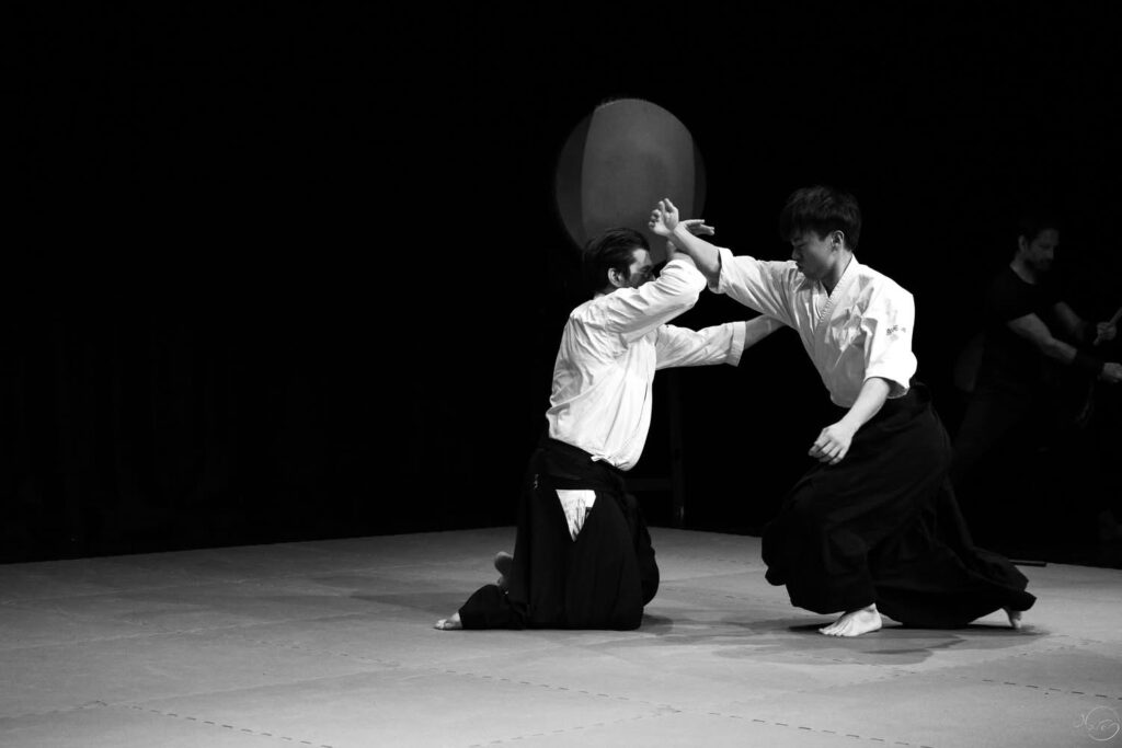 two men in white shirts and black skirts on a stage